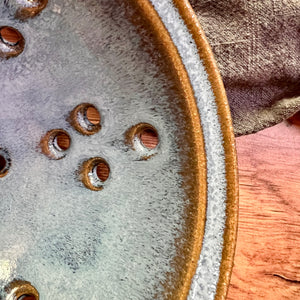 Detail image of Pint size berry colander. Wheel thrown pottery, red stoneware shown in Icy Blue glaze.
