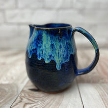 Load image into Gallery viewer, wheel thrown and handcrafted stoneware pottery pitcher in Blue world glaze. The pitcher is a dark cobalt blue on the bottom layer with a unique layering of  turquoise and bright blue dripping down the top half of the pitcher.