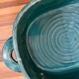 detail image of a Casserole dish in Teal glaze with Iced rim. wheel thrown and altered, with pulled handles added. made with stoneware clay.