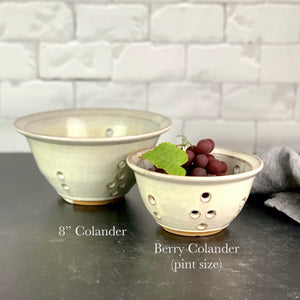 an 8"diameter colander and a pint sized Berry colander in speckled white glaze