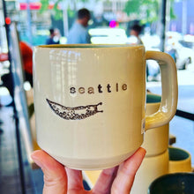 Load image into Gallery viewer,  Wheel thrown pottery mug with &quot;seattle&quot; and an image of a banana slug inset on the outside. white outside, turquoise green glaze interior