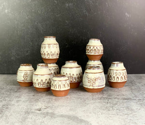a collection of small bud vases. the vases are about 1.5-2 inches tall, wheelthrown in red stoneware,  and each one is hand carved.