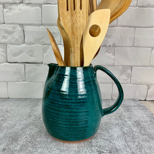 Teal pottery pitcher on red stoneware clay, shown here being used as a utensil holder