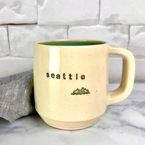  Wheel thrown pottery city mug with "seattle" and an image of a ferry inset on the outside. white outside, turquoise green glaze interior