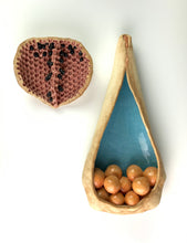 Load image into Gallery viewer, closeup, detail shot of See Pod inspired wall sculpture, stoneware husk like nest of seeds or eggs in light orange with a blue interior. shown here hanging with another seedpod sculpture