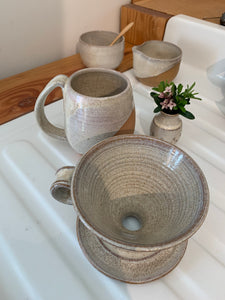 showing the inside of a pottery coffee pour over. notice the wheel thrown pattern inside the cone shape. also shown in the background: matching mug, cream and sugar set and carved bud vase. Fern Street Pottery