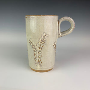 Pottery travel mug with finger loop handle. thrown on the pottery wheel, red clay, carved with vine pattern, white speckled glaze