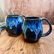 Load image into Gallery viewer, Blue World Mugs! a dark blue glaze base on a red stoneware mug. the top of the mug is glazed in layered blue glazes that undulate and drip. Each one is unique. Holds 14-16 oz and has a full handle grip with groovy thumb groove.