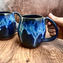 Load image into Gallery viewer, Blue World Mug! a dark blue glaze base on a red stoneware mug. the top of the mug is glazed in layered blue glazes that undulate and drip. Each one is unique. Holds 14-16 oz and has a full handle grip with groovy thumb groove.