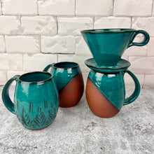 Load image into Gallery viewer, Set of ceramic mugs with a coffee pour over on one. one carved mug, two angle dipped mugs in teal.