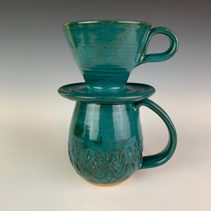 wheel thrown and hand carved mugs. the mug is thrownin red stoneware and glazed in a beautiful rich teal. the mugs have delicate patterns carved into them. shown here in the fern/tree carved pattern, with a matching pour over