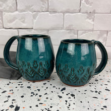 Load image into Gallery viewer, Beautiful, vibrant teal glaze on hand carved northwest mugs. the carvings allow the glaze to show through a bit at the edges, bringing variation to the glaze.
