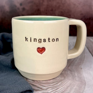  Wheel thrown pottery city mug with the word "kingston" and a red heart inset on the outside. white outside, turquoise green glaze interior