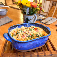 Load image into Gallery viewer, Casserole dish in cobalt Blue World glaze. shown with a spaghetti squash baked in it. wheel thrown and altered, with pulled handles added. made with stoneware clay.
