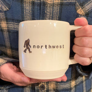 Sasquatch image with the word "northwest" impressed into the side.  an artist made, wheel thrown pottery mug. Beautiful porcelaina creamy white clay with a turquoise glaze on the inside.