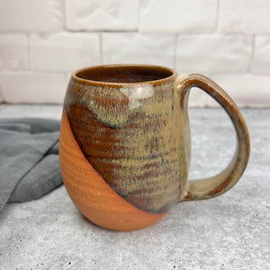 Wheelthrown mug, handcrafted with pulled handle. Angle dipped glaze pattern which leaves some of the natural red clay exposed for a tactile experience. This mug is shown in "caramel" which is a beautiful glaze that shows the beautiful layers and transparency.