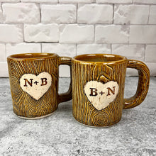 Load image into Gallery viewer, Large custom coffee mugs with lumberjack, woodgrain pattern impressed and carved in for texture you can feel. the mugs have a heart carved into them with initials, like lovers would carve into a tree