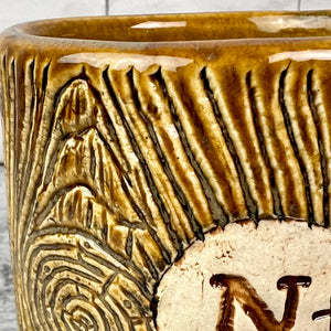 Detail photo of a lumberjack mug showing the textures and detail carved into the clay. the glaze seeps into the carved texture.