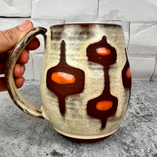 Load image into Gallery viewer, Handcrafted, wheel thrown mug by Meredith Chernick at Fern Street Pottery. Hand painted resist and glaze pattern in light dijon yellow, deep red stoneware clay, and bright orange dots. 
