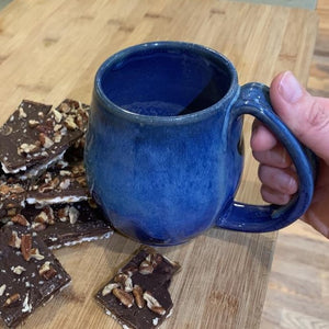 Blue world mug, northwest style coffee mug thrown pottery, with large pulled handle with groovy thumb groove. shown with matzah roca cookies