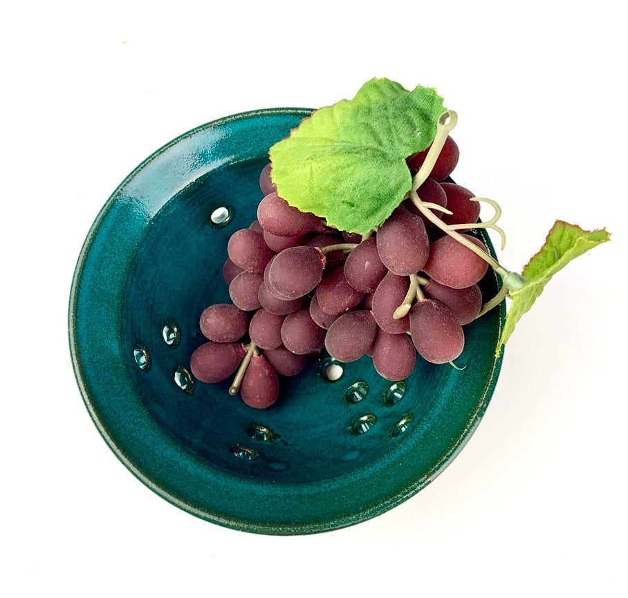 Berry colander in teal glaze on red clay. shown with rinsed  grapes