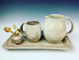 carved bud vase shown with carved mug, carved rim platter and pitcher in speckled white.