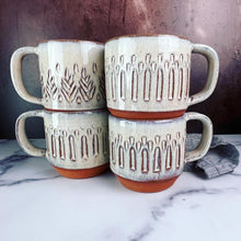 Load image into Gallery viewer, stackable mugs. A collection of wheelthrown carved mugs glazed in rustic white glaze. the carved facets show through the white glaze. 
