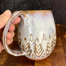Load image into Gallery viewer, wheel thrown and hand carved mugs. the mug is thrownin red stoneware which shows throught the white glaze at the edges of the mug. the mugs have delicate patterns carved into them. shown here in the fern/tree carved pattern