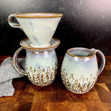Load image into Gallery viewer, wheel thrown and hand carved mugs. the mug is thrownin red stoneware which shows throught the white glaze at the edges of the mug. the mugs have delicate patterns carved into them. shown here in the fern/tree carved pattern, with a matching coffee pour over