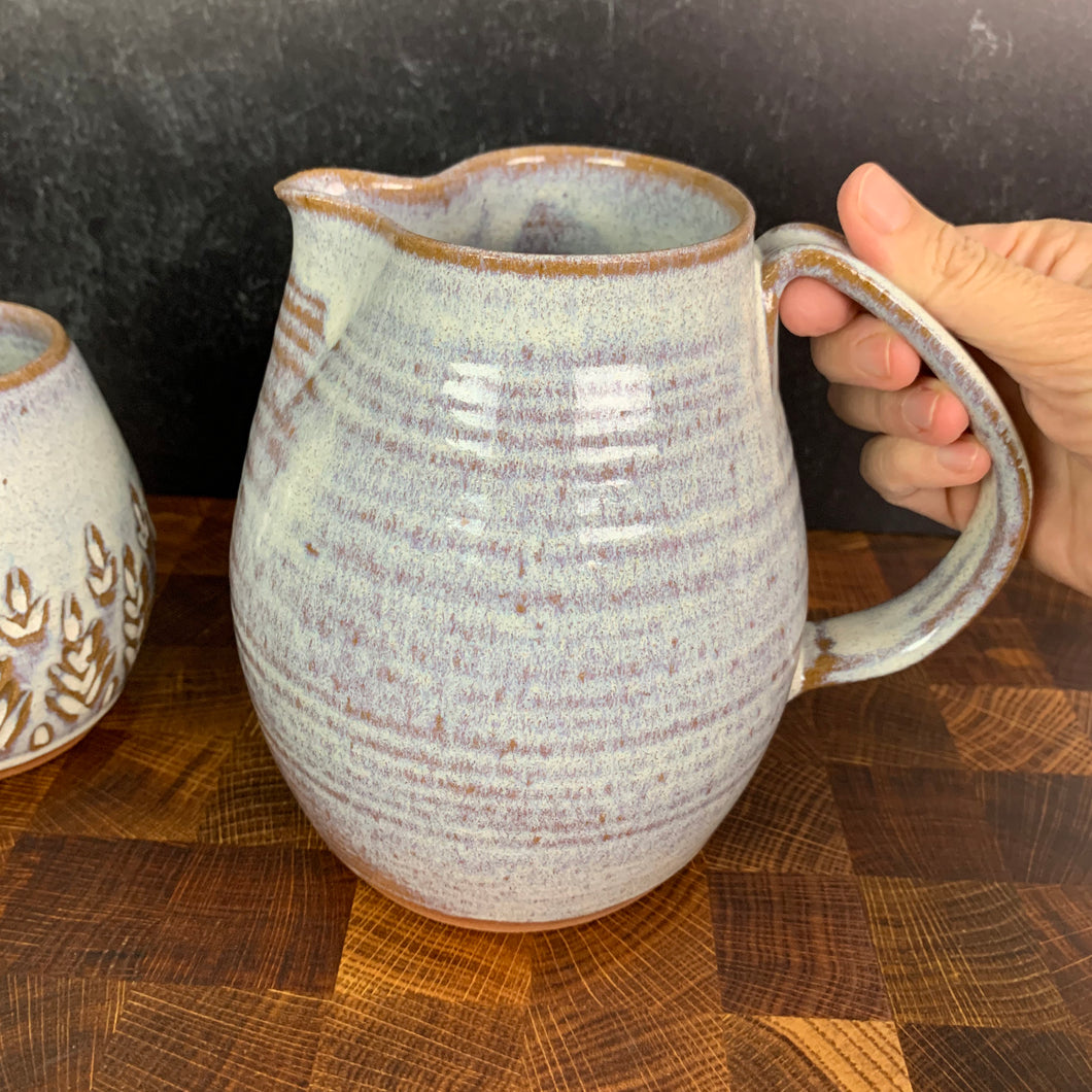wheel thrown pottery pitcher shown in rustic white with pulled handle. handcrafted and wheel thrown at  Fern Street Pottery