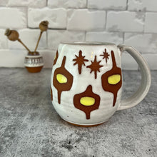 Load image into Gallery viewer, wheelthrown Pottery mug, hand glazed with MidMod pattern in white, and yellow, with the deep red clay showing in the resist pattern. this one has starburst patterns in resist as well