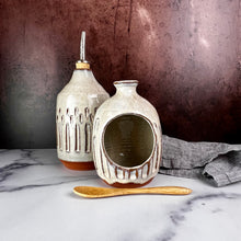 Load image into Gallery viewer, Olive oil cruet, shown with salt cellar. Wheel thrown and carved. cork stopper  for smooth pouring. Thrown in a red stoneware clay and carved by hand. the white glaze accentuates the carved pattern where the red clay shows through.