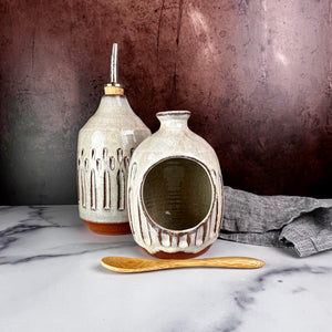 Olive oil cruet, shown with salt cellar. Wheel thrown and carved. cork stopper  for smooth pouring. Thrown in a red stoneware clay and carved by hand. the white glaze accentuates the carved pattern where the red clay shows through.