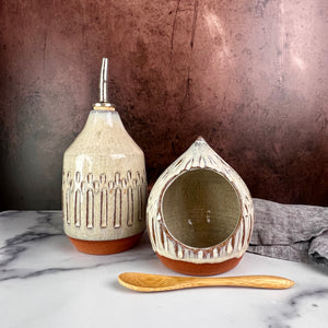 Salt Cellar, also known as a salt well or salt pig. shown here with matching Olive oil cruet. Wheel thrown and carved in a traditional onion dome shape.. comes with a bamboo spoon and a starter sea salt packet.. Thrown in a red stoneware clay and carved by hand. the white glaze accentuates the carved pattern where the red clay shows through.