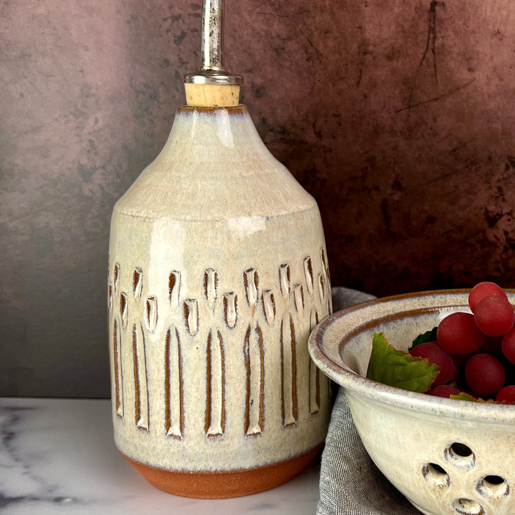 Olive oil cruet. Wheel thrown and carved. cork stopper  for smooth pouring. Thrown in a red stoneware clay and carved by hand. the white glaze accentuates the carved pattern where the red clay shows through.