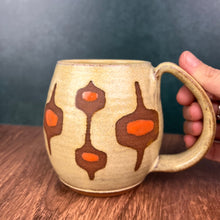 Load image into Gallery viewer, MidMod mug- freshly made vintage style. This mug features a soft dijon yellow glaze with orange accent spots showing through the midmod design resist in a deep rust red stoneware clay. full fingered handle with groovy thumb groove.