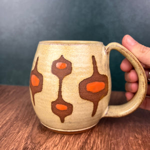 MidMod mug- freshly made vintage style. This mug features a soft dijon yellow glaze with orange accent spots showing through the midmod design resist in a deep rust red stoneware clay. full fingered handle with groovy thumb groove. Fern Street Pottery