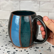 Load image into Gallery viewer, Stripe mug with Teal, Turquoise, and Stardust (black glitter!)glaze hand painted on. red stoneware clay shows through between the stripes 