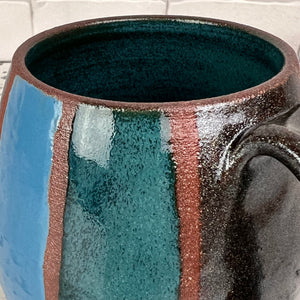 Detail shot of the Stripe mug with Teal, Turquoise, and Stardust (black glitter!)glaze hand painted on. red stoneware clay shows through between the stripes . Fern Street Pottery