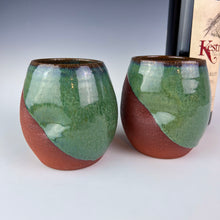 Load image into Gallery viewer, Stemless wine glasses. set of two wheel thrown pottery with finger divots for grip. Mottled green glaze over red stoneware clay, glazed at an angle to reveal the clay. shown with wine
