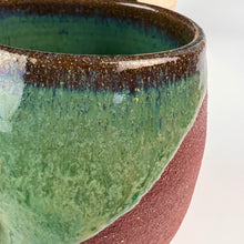Load image into Gallery viewer, detail shot of glaze on Deep green wine glass. showing the deep red clay and the detail of the glaze. note the blues and browns on the rim
