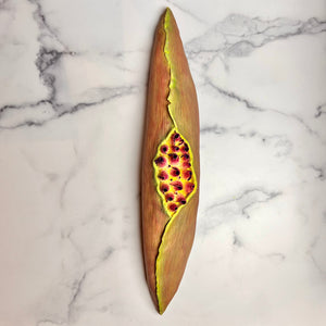 full image of a seedpod sculpture by meredith chernick of fern street pottery. the sculpture is made of porcelain and cold finished in bright colors with smooth hombre blends. this sculpture depicts a seedpod's husk with small protrusions emerging from within.