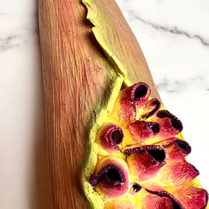 closeup image of a seedpod sculpture by meredith chernick of fern street pottery. the sculpture is made of porcelain and cold finished in bright colors with smooth hombre blends. this sculpture depicts a seedpod's husk with small protrusions emerging from within.