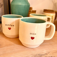 Load image into Gallery viewer, Mom love mug and a coffee love mug, each with a heart stamped into the mug under the text. White clay, turquoise glaze on the inside. this mug was wheel thrown and hand stamped and colored at fern street pottery.