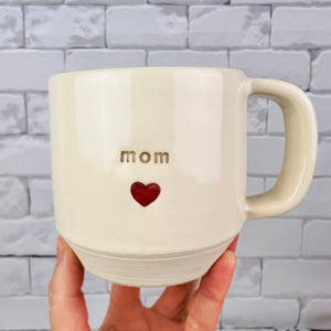 Mom love mug, with mom and a heart stamped into the mug. White clay, turquoise glaze on the inside. this mug was wheel thrown and hand stamped and colored at fern street pottery.