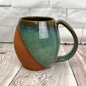Wheel thrown and hand crafted in red-brown stonware clay, this angle dipped mug is featured in a drippy moss green glaze. beautiful color and textures. holds 14-16 oz