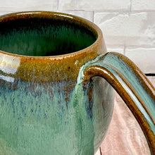 Load image into Gallery viewer, detail image of moss green angle dipped mug. Wheel thrown and hand crafted in red-brown stonware clay, this angle dipped mug is featured in a drippy moss green glaze. beautiful color and textures. holds 14-16 oz