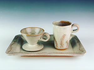 serving platter (14" x 9.5") in carved, speckled white, shown with  matching travel mug and coffee pour over