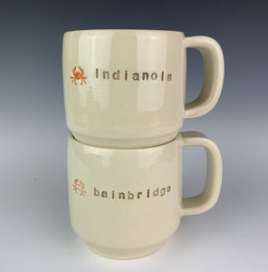two cylindrical mugs, wheel thrown, pottery, hand made and with city names pressed into them, and also a cute little image of a crab. 
