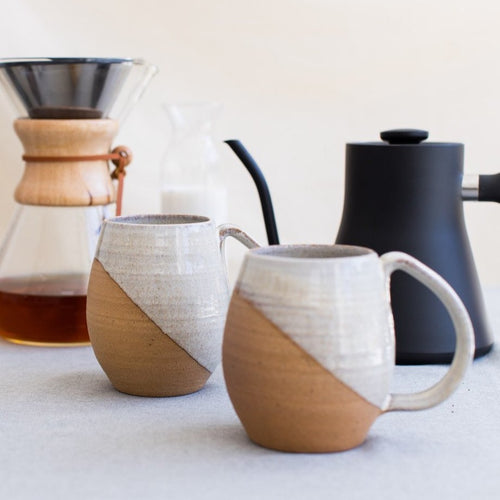 angle dipped mugs in speckled white glaze. wheel thrown in stoneware. shown with contemporary, classic coffee products
